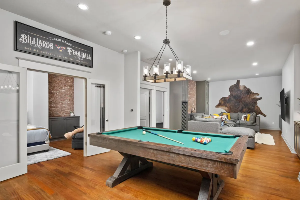 A playful recreation area centered around a stylish billiard table, complemented by a comfortable sofa, elegant chandelier, and decorative wooden wall art. The atmosphere is relaxed yet social, perfect for friendly matches and inclusive gatherings.