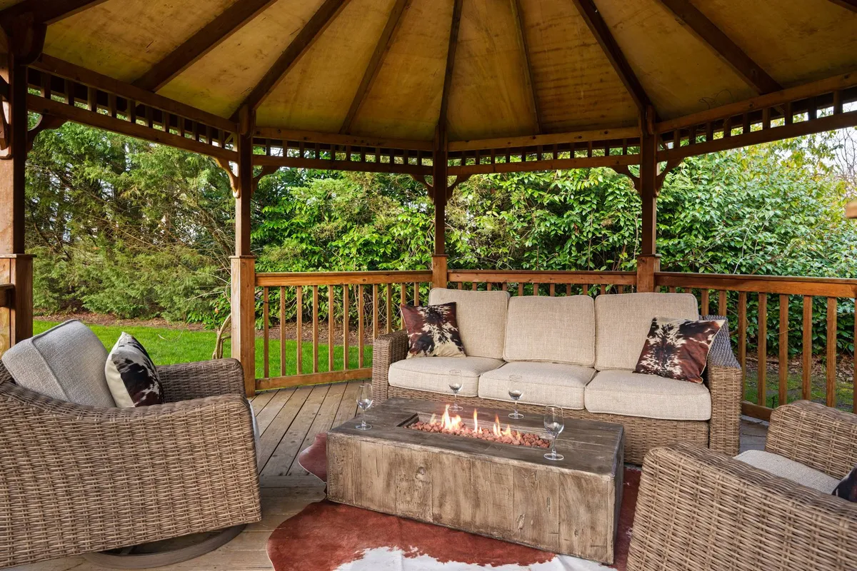A cozy outdoor fire pit area is surrounded by inviting seating and bordered by vibrant greenery. The fire pit is the focal point, perfect for group gatherings and evening stories under the open sky.