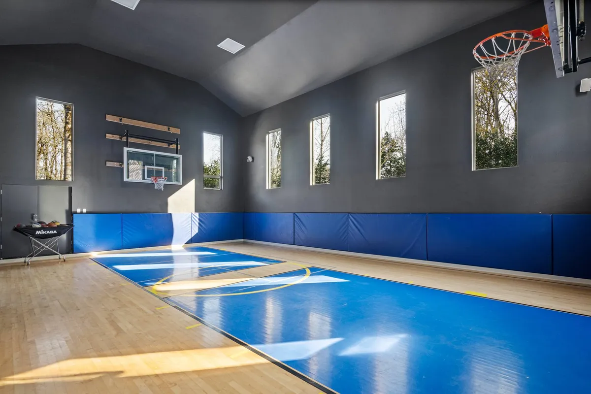 A bright indoor basketball court featuring a prominent basketball hoop, polished wooden floors, and large windows that flood the space with natural light. The design encourages active play and group gatherings in a lively and inviting environment.