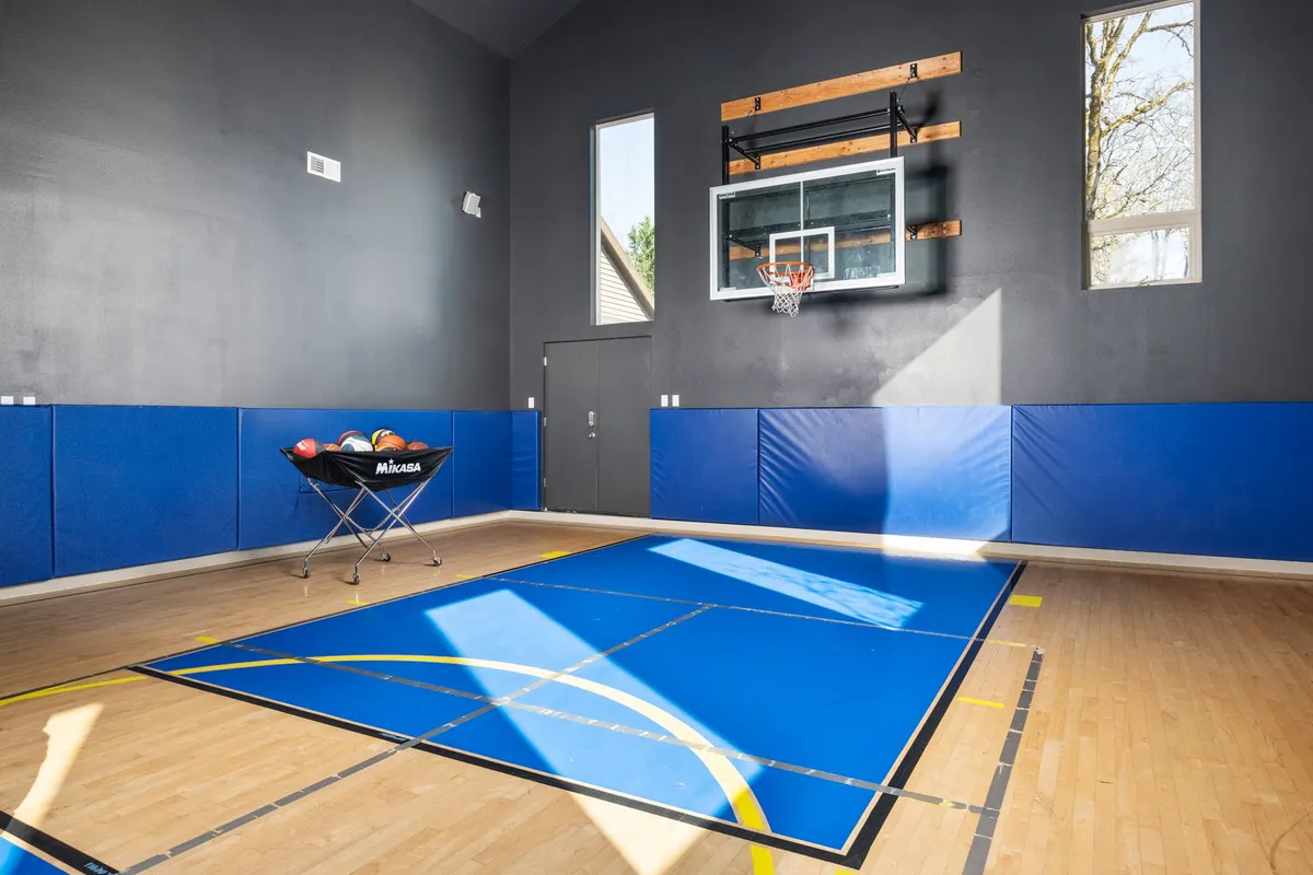 A vibrant, active interior space showcasing a full basketball court with a hoop and exercise equipment. The environment encourages recreational play, fitness activities, and friendly family competitions—an exciting amenity for kids and teens.