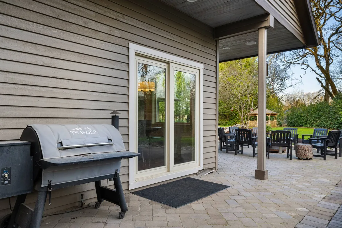 An inviting outdoor patio with a barbecue grill, comfortable patio furniture, and easy access to the house via a sliding glass door. The setup signals opportunities for outdoor dining, sunset barbecues, and social gatherings in a relaxed atmosphere.