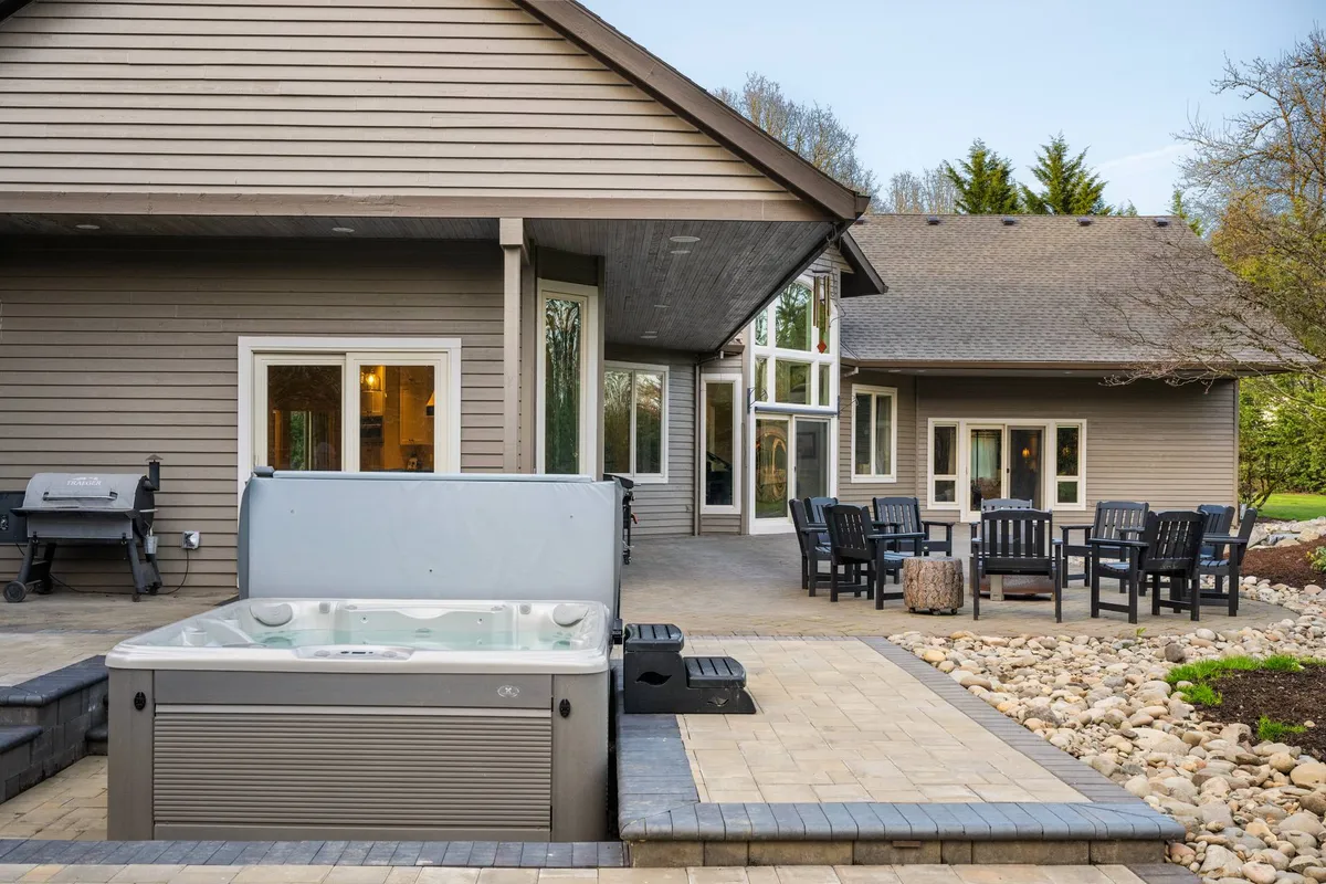 This photo captures the outdoor hot tub and patio area, complete with comfortable seating and large windows that connect indoor and outdoor living. The scene exudes a sense of relaxation and sociability, perfect after a day of vineyard visits.